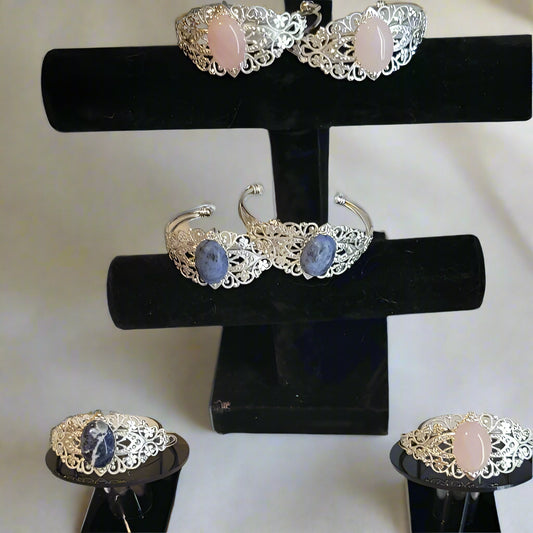 Set of silver rings with gemstones on a black stand against a gray background